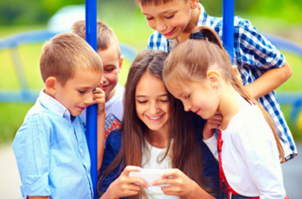 Девочка сидит в телефоне, ее окружили друзья