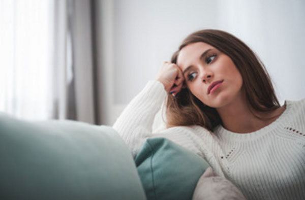 Грустная женщина сидит на диване