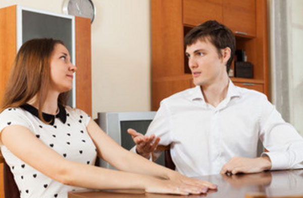 Парень разговаривает с девушкой, сидя за столом