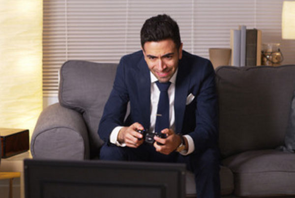 Мужчина в костюме сидит на диване и играет в компьютерную игру