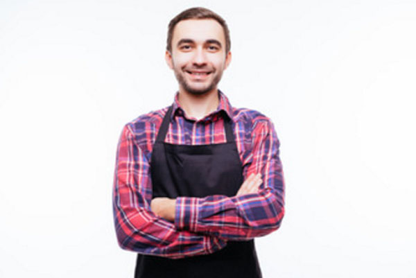Мужчина в фартуке стоит и улыбается