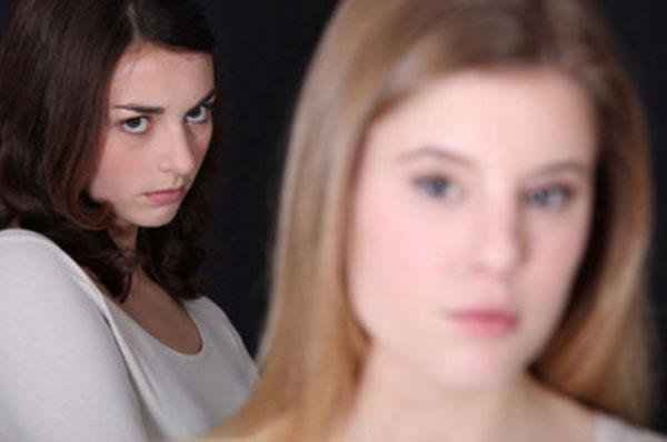 На переднем плане размытое лицо девушки. На заднем - обиженная девушка с серьезным выражением лица