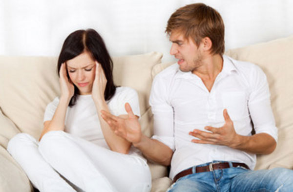 Мужчина сидит на диване рядом с женщиной, кричит на нее