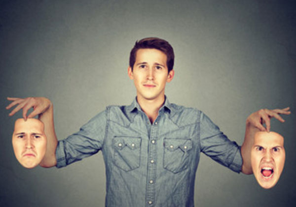 Мужчина с нормальным выражением лица держит в руках два своих лица, депрессивное и агрессивное