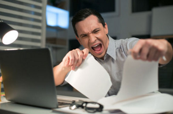 Мужчина в нервном напряжении рвет листы бумаги