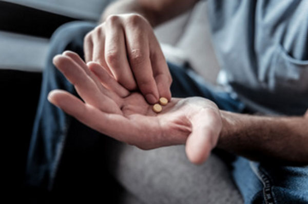 Ладонь мужчины, на которой лежит две таблетки