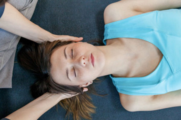 Женщина лежит на кушетке. ей массажируют голову