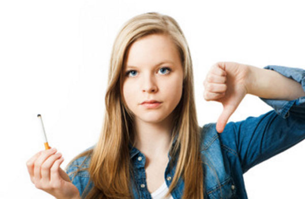Девочка - подросток держит в руке сигарету и показывает палец вниз