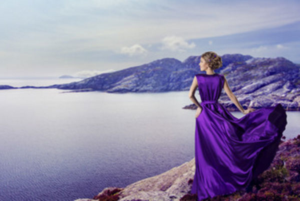 Женщина в фиолетовом платье стоит на берегу