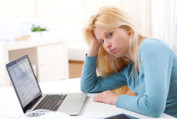 Замученная женщина сидит за ноутбуком