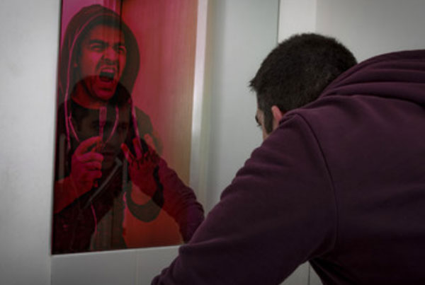 Мужчина смотрит в зеркало и видит в нем себя, желающего покончить с жизнью