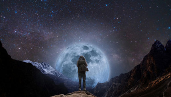 Человек стоит на возвышенности. Перед ним огромная луна