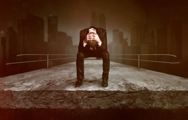 Человек сидит на стуле у обрыва, держится за голову