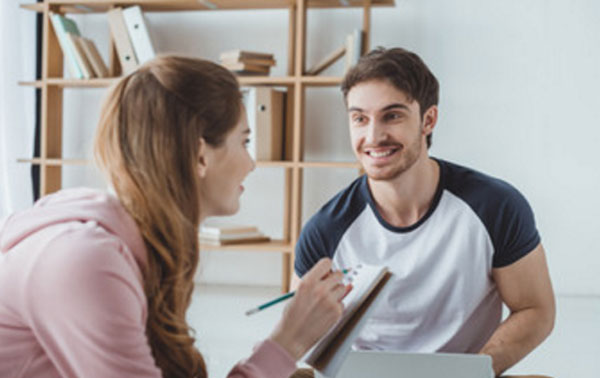 Парень с девушкой что-то обсуждают, сидя на полу