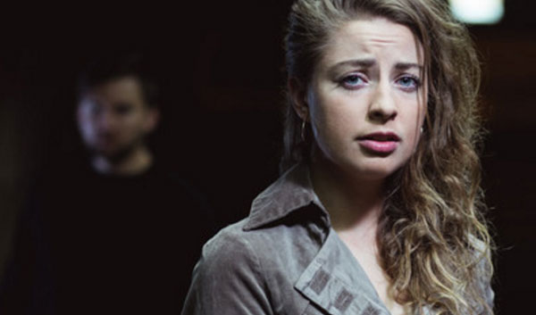 Напуганная девушка. На заднем плане мужчина