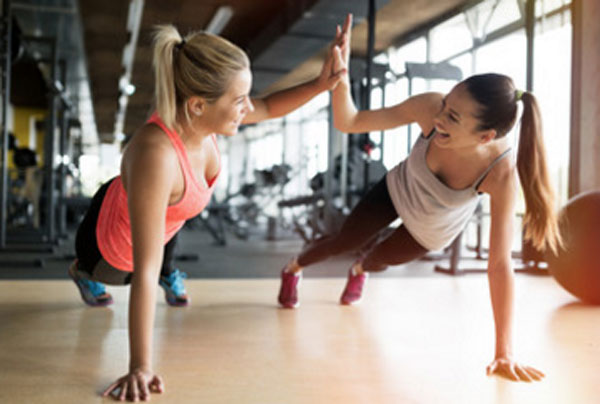 Две девушки держат планку в тренажерном зале