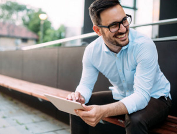 Мужчина в очках сидит на улице и улыбается