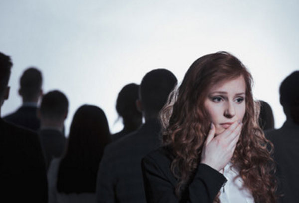На переднем плане женщина, которая держится за лицо. На заднем толпа людей, повернутых спиной к ней