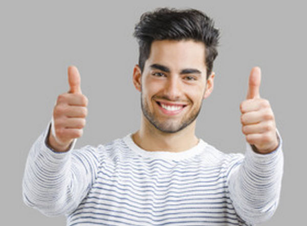 Молодой улыбающийся мужчина поднимает оба больших пальца вверх