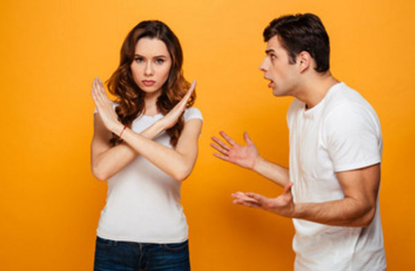 Парень что-то кричит на парня. Девушка стоит, скрестив руки