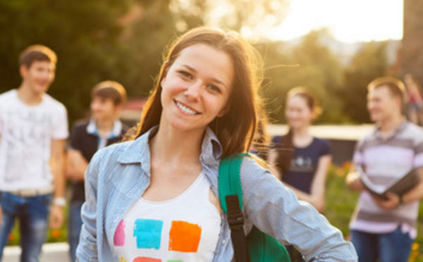 Студентка улыбается. На заднем плане еще студенты