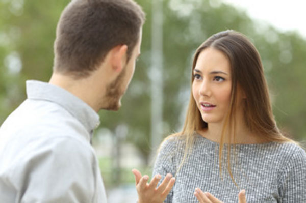 Парень стоит лицом к девушке, она что-то пытается ему объяснить