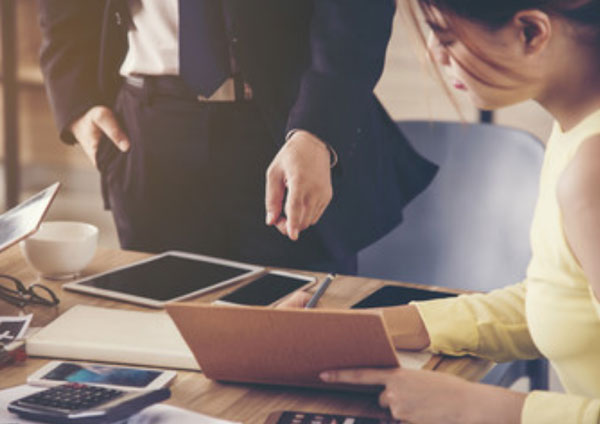 Девушка что-то пишет. Мужчина на что-то ей указывает