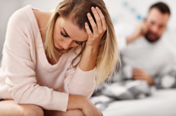 На заднем плане мужчина говорит по телефону. На переднем - расстроенная девушка