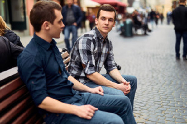 Два парня сидят на скамейке