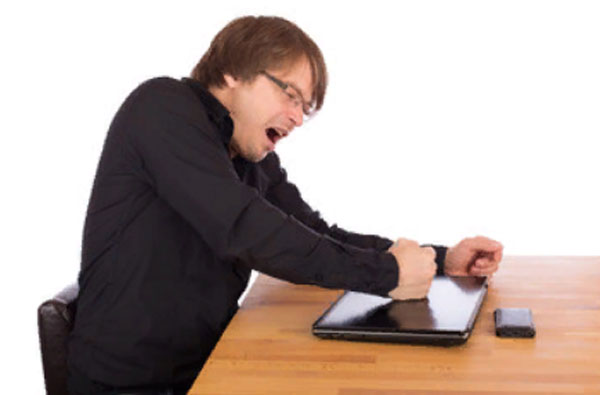Вспыльчивый мужчина бьет кулаком по ноутбуку