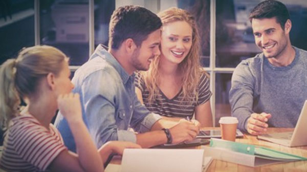 Два парня и две девушки обсуждают работу за общим столом