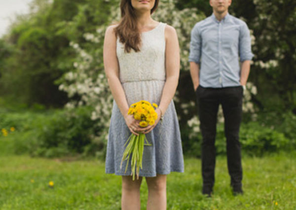 На переднем плане девушка с цветами. На заднем - парень