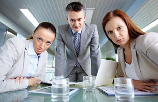 Коллеги зло смотрят, две девушки сидят за столом и мужчина стоит