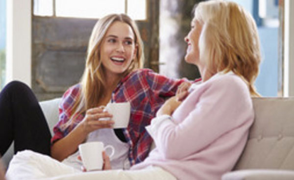 Мама с дочкой весело беседуют за чашкой чая