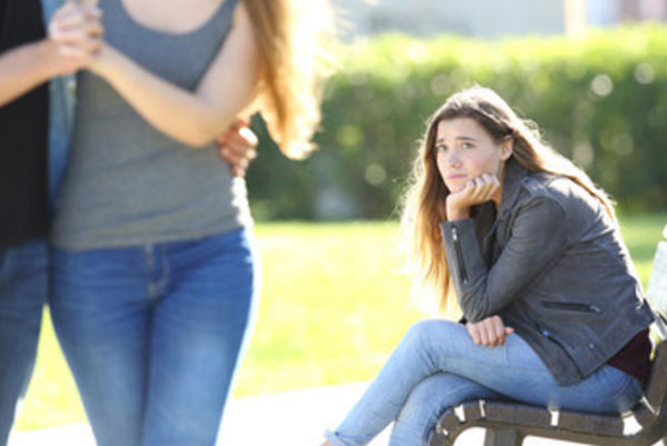 Девушка с завистью смотрит на проходящую мимо пару