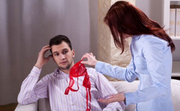 Женщина скандалит с мужчиной, держа в руке красный бюсгалтер