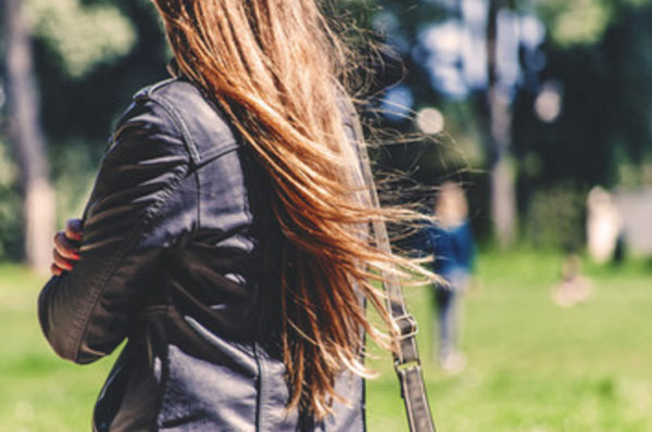 Женщина со сложенным руками идет по улице и смотрит в сторону человека, стоящего в далеке