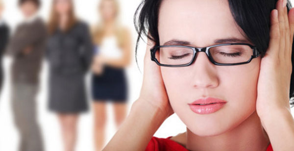 Женщина в очках с закрытыми глазами и ушами. На заднем плане стоят женщины