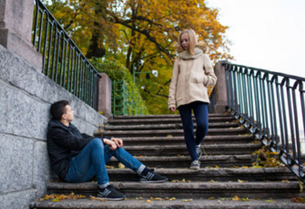 Парень сидит на ступеньках, мимо проходит девушка и смотрит на него