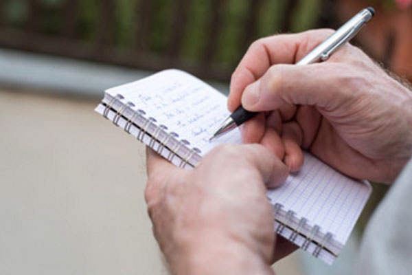 Мужчина пишет какой-то список в блокноте