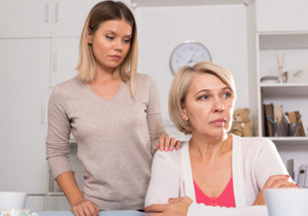 Дочка подошла сзади к сидящей за столом печальной матери