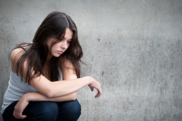 Грустная девушка сидит на корточках