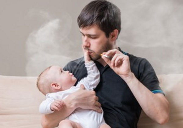 Курящий мужчина с грудничком в руках