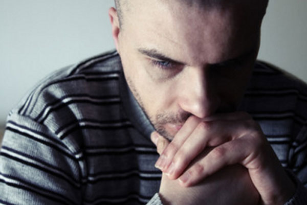 Грустный мужчина сидит в задумчивости