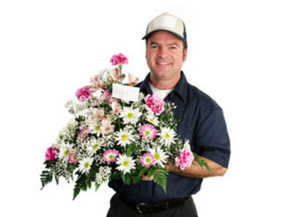 Улыбчивый курьер с букетом цветов, в который вставлена записка