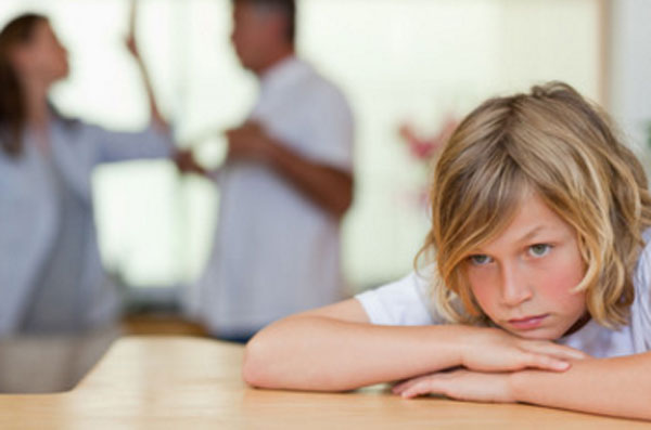 Грустный ребенок. На заднем плане ругаются родители