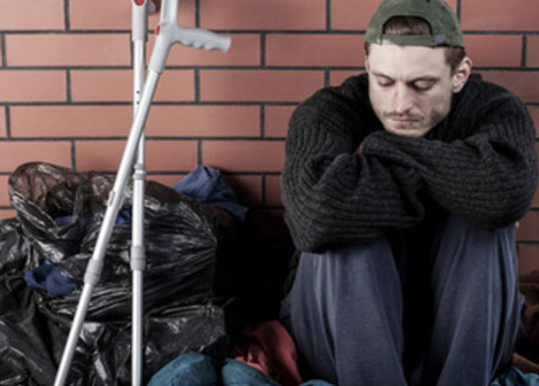 Мужчина сидит на земле. Рядом с ним стоят костыли