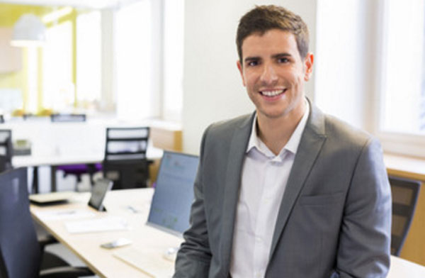 Улыбающийся мужчина в костюме. Он находится в офисе