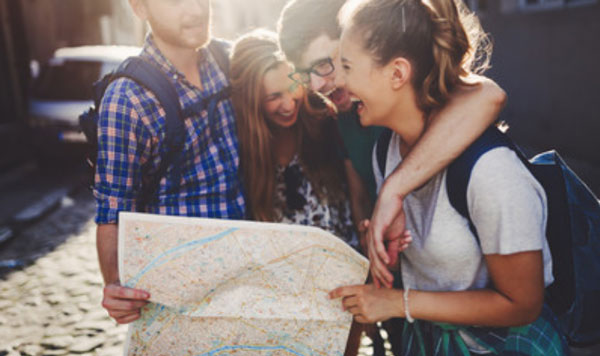 Два парня и две девушки стоят с картой в руках. Им весело