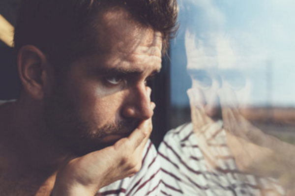 Апатичный мужчина смотрит в окно